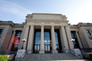 The image shows the front view of the Missouri History Museum, featuring a neoclassical facade with tall columns, a grand entrance, and the words "Jefferson Memorial" inscribed above.