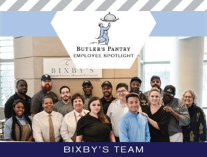 Group photo of Bixby’s team at the Missouri History Museum. The team members, wearing various professional attire, are standing together and smiling. A sign above reads "Butler's Pantry Employee Spotlight.