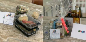A table displaying two sections: on the left, a selection of packaged meals and snacks, each labeled; on the right, a gift basket containing drinks and a wrapped item with a bow and a card labeled "COCA.