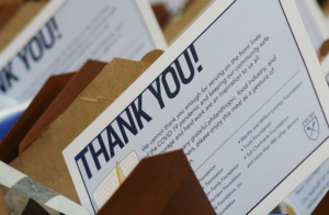 A thank you card placed among several others, expressing gratitude to front line workers for their efforts during the COVID-19 pandemic. The card features a message of appreciation and a heart illustration.