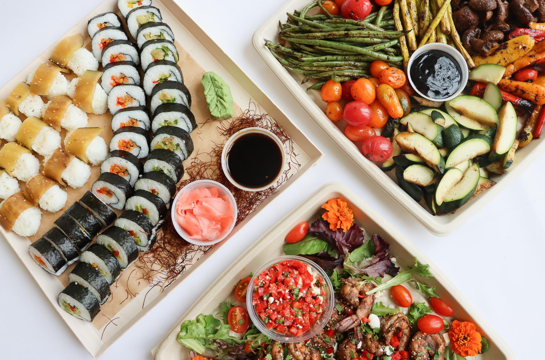 Assorted sushi rolls, grilled veggies, and a mixed salad with chicken and salsa on square plates.