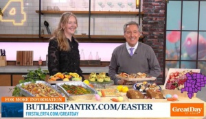 Two people smiling in a studio kitchen with various Easter dishes displayed on the counter.